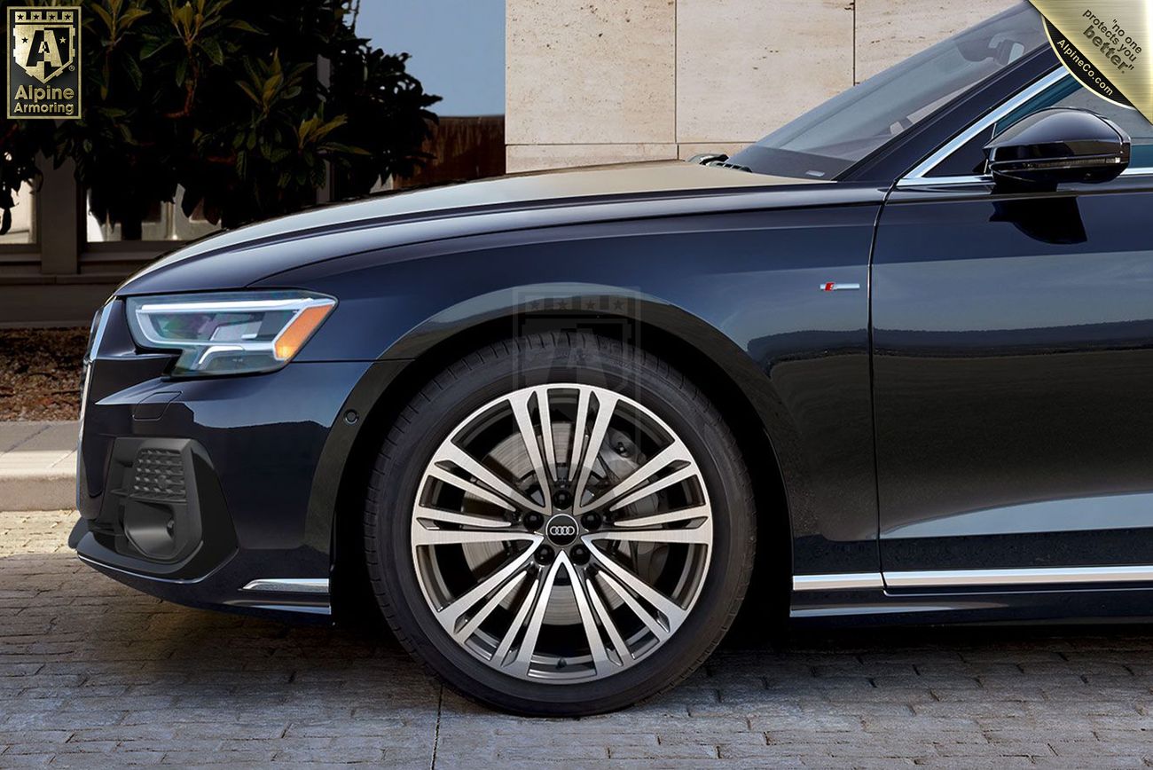 Side view of a black armored Audi A8 sedan displaying the front wheel, part of the front bumper, and a badge on the fender.