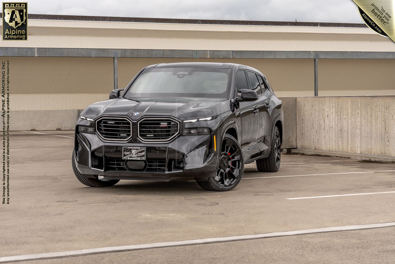 Black BMW XM with distinctive large grille parked in concrete parking structure.