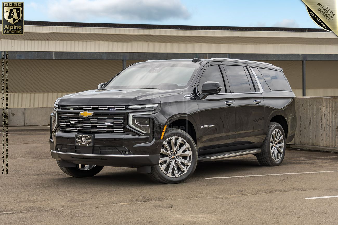 Black Chevrolet Suburban SUV with chrome grille and multi-spoke wheels parked in concrete structure.