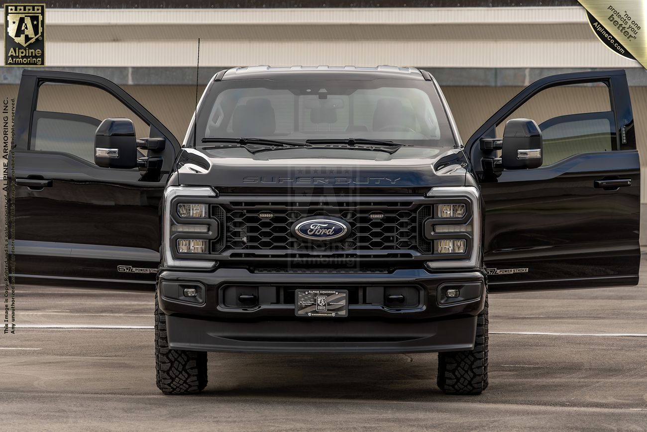 Black Ford F-350 Super Duty pickup truck with front doors open, showing bold mesh grille and stacked LED headlights in parking structure.