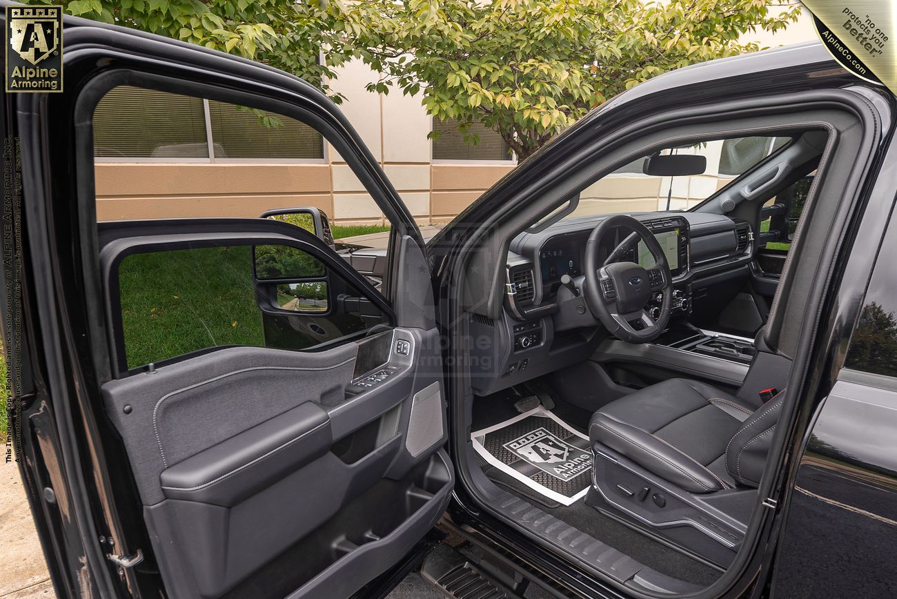 Interior view of an open black Ford F-350 door, showing the driver's seat, dashboard, and steering wheel. The truck features a two-tone interior with black and dark gray elements.