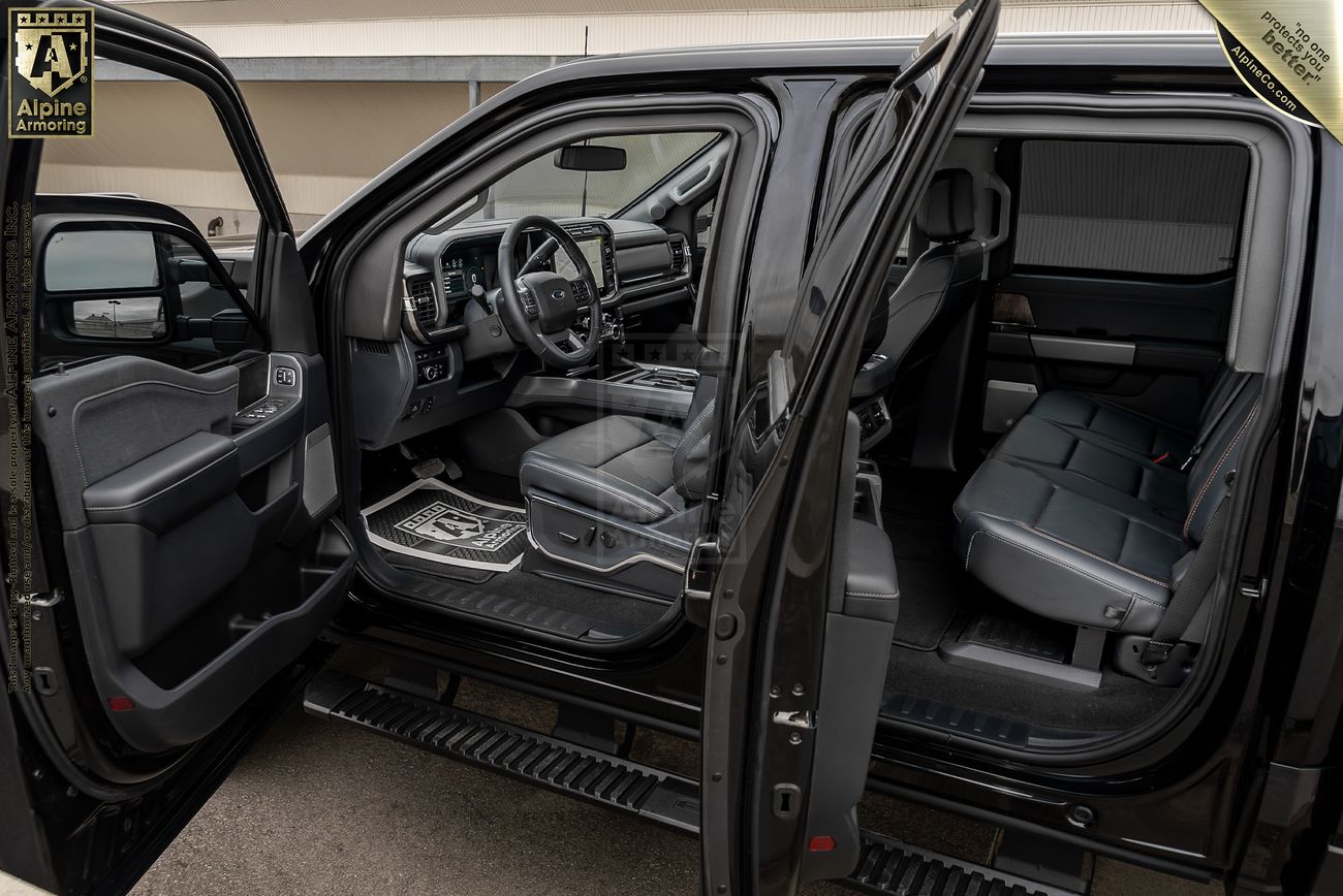 Interior view of an open black Ford F-350, showing front and back seats with detailed dashboard, steering wheel, and door panel.