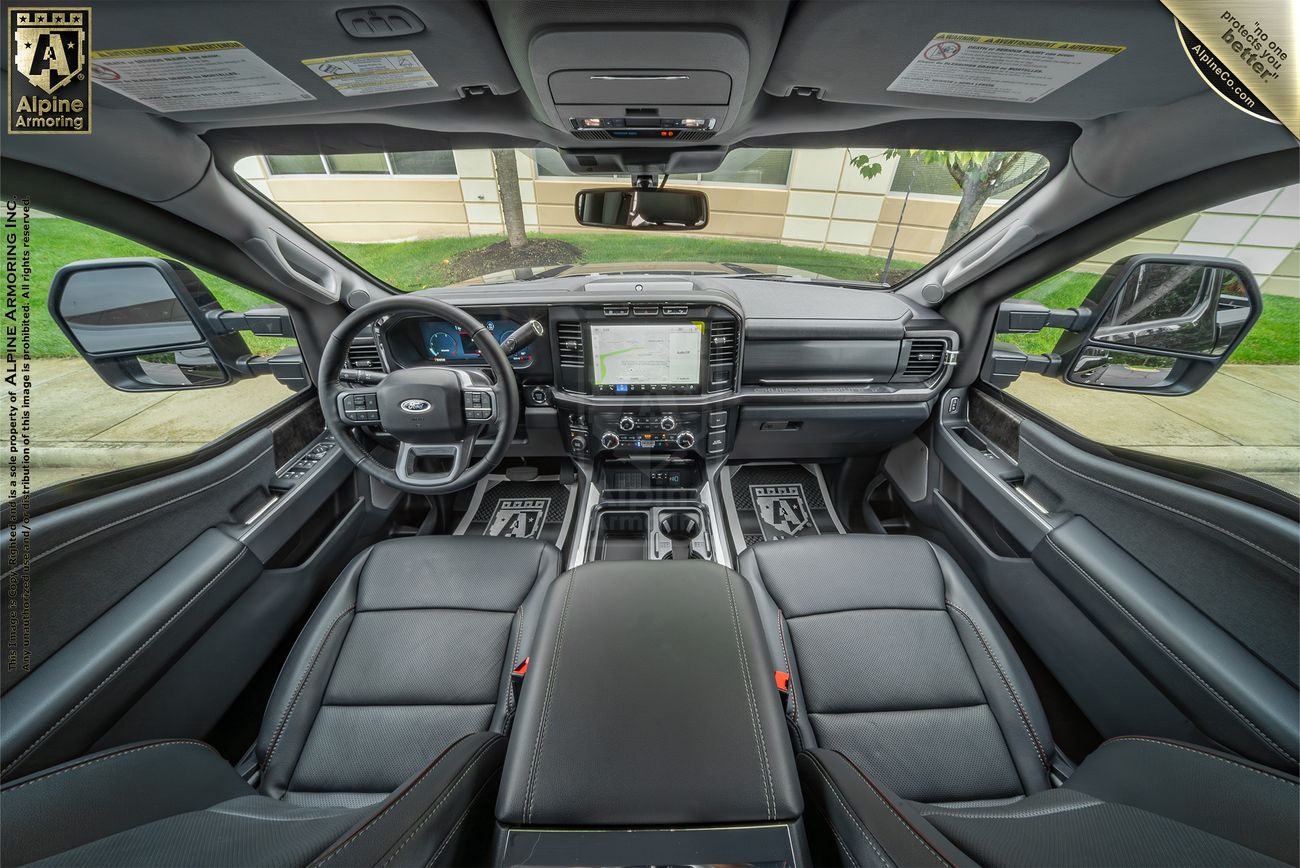 Interior view of a Ford F-350 cabin featuring leather seats, a large touchscreen on the dashboard, a steering wheel with controls, and various technical and comfort features.