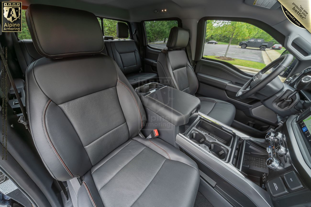 Interior of a Ford F-350 featuring black leather seats, a central console with cup holders, and a dashboard with various controls visible. The vehicle is parked outdoors.