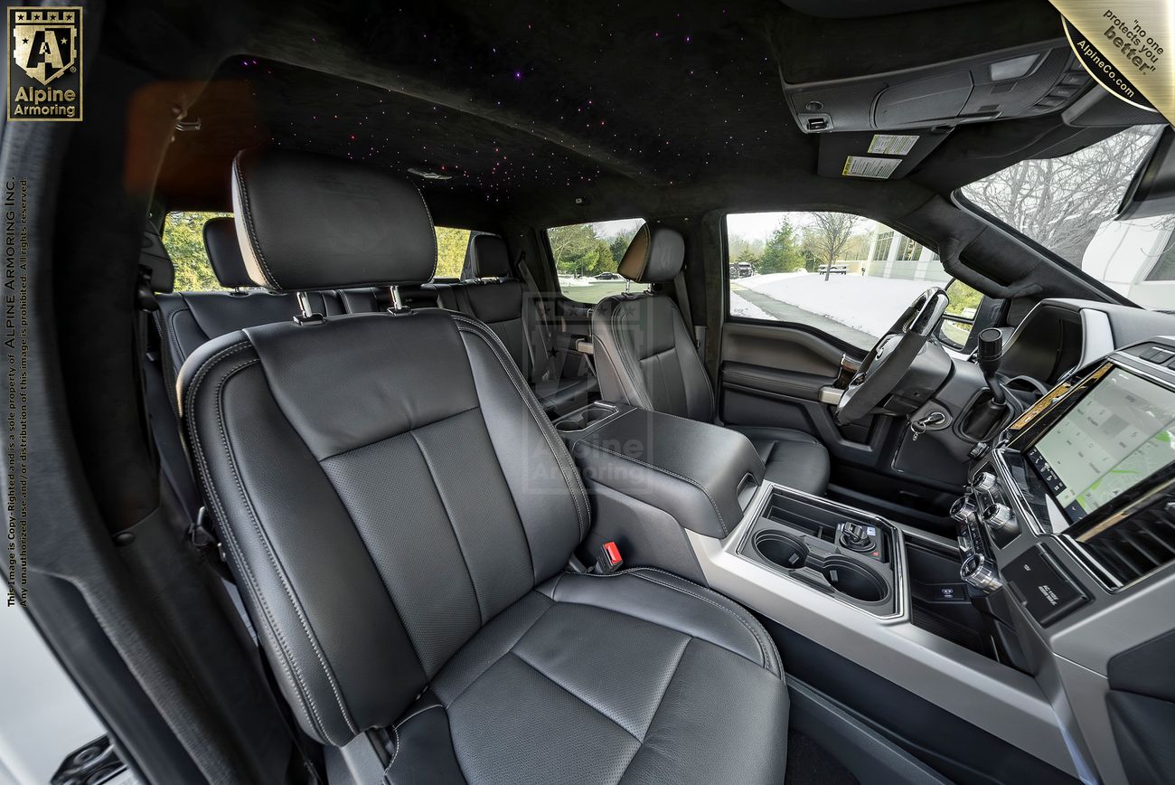 Interior view of a Mastiff with black leather seats, a large touchscreen display, and multiple control panels, showcasing a sleek and spacious design.