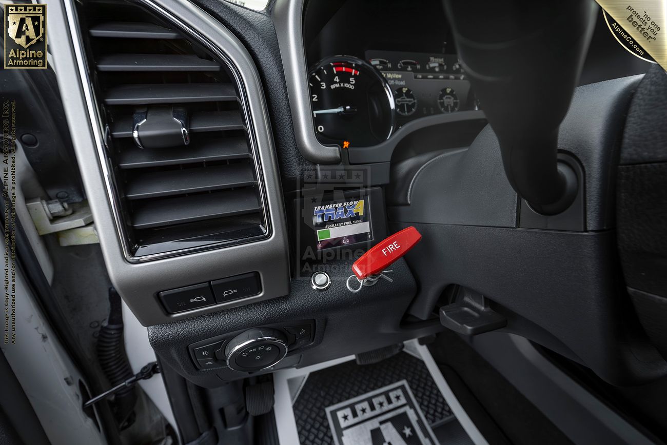 Close-up of a Mastiff  dashboard with a "Fire" pull handle, vent, gauge cluster, and Alpine Armoring logo visible.
