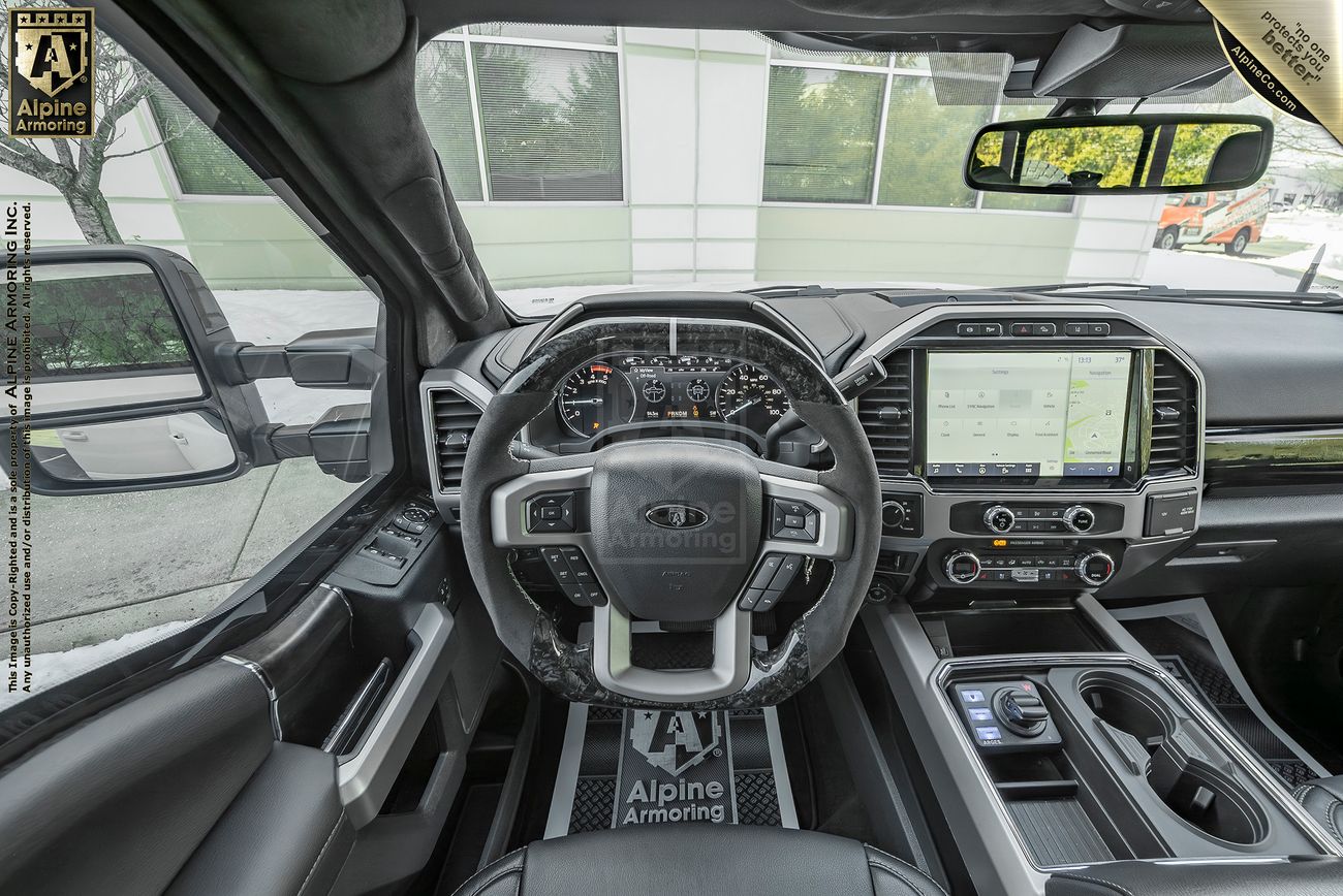 Interior view of a Mastiff's driver's cockpit, featuring a large touchscreen display, leather-wrapped steering wheel, and various controls on the dashboard and center console.