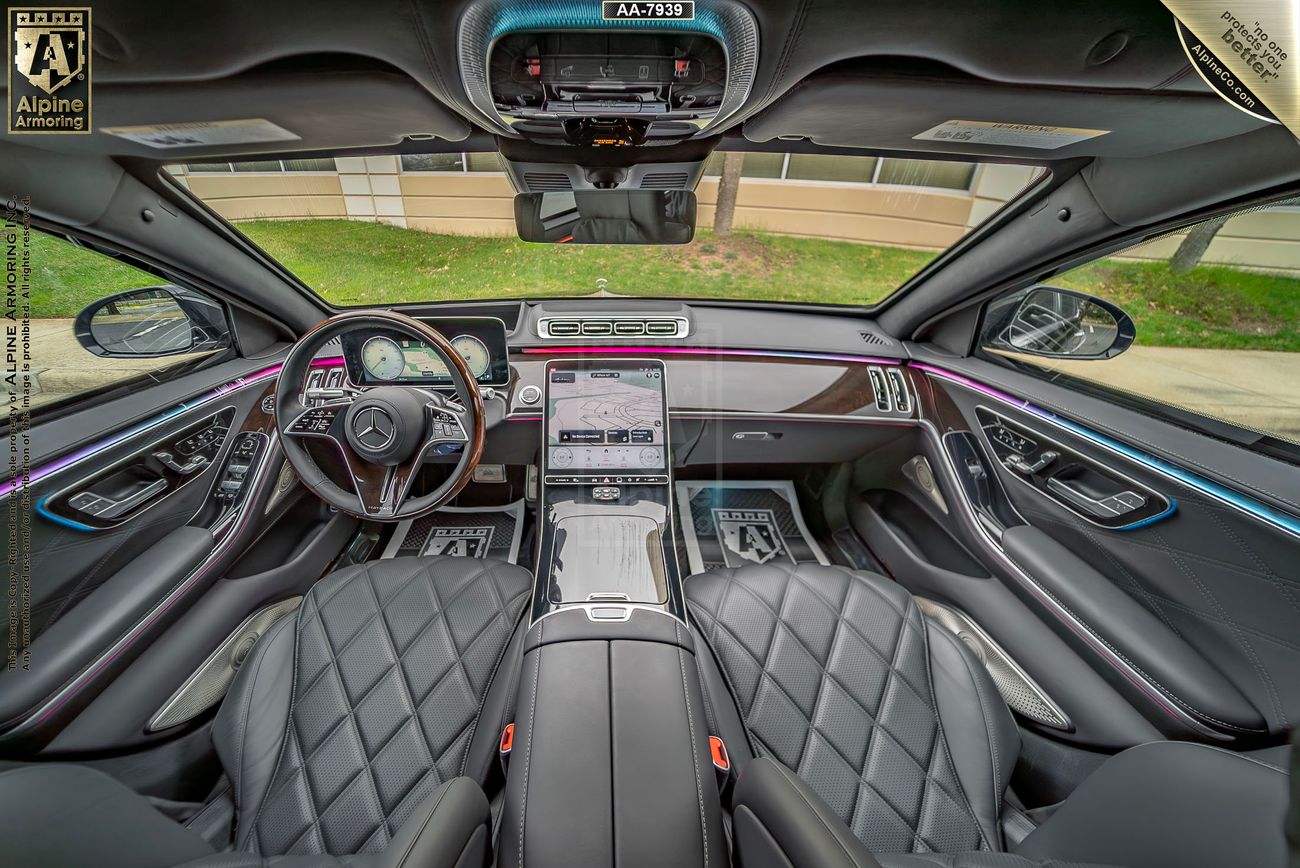 Interior view of a luxurious Mercedes-Benz Maybach, featuring a panoramic sunroof, diamond-stitched leather seats, a large touchscreen display, and ambient lighting. The car dashboard showcases a high-tech design.