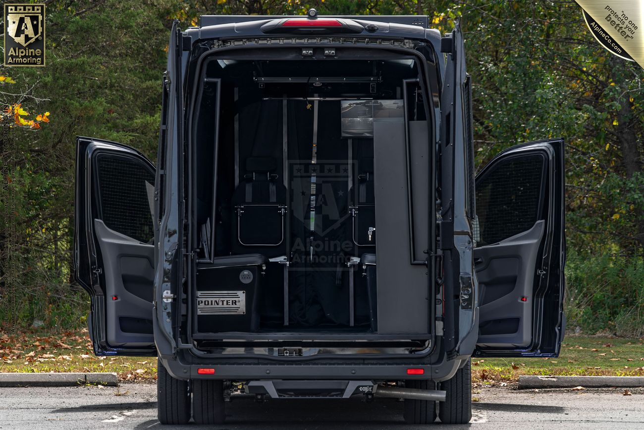 A black Pointer van with its rear doors open, revealing organized interior equipment. The van is parked on a paved surface with green foliage in the background.