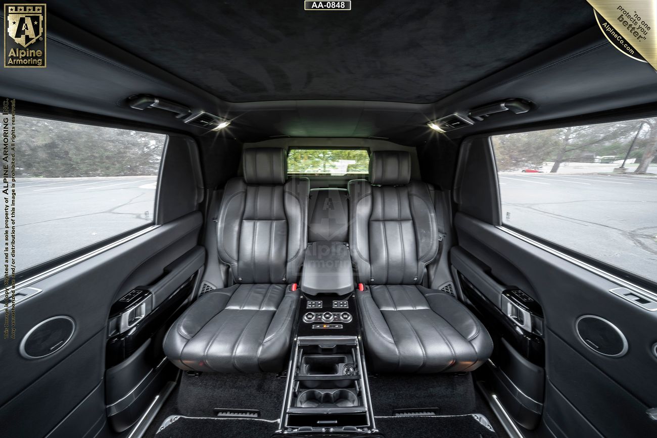 Luxurious car interior featuring black leather seats, a central console with controls, and side windows showcasing an outdoor view.