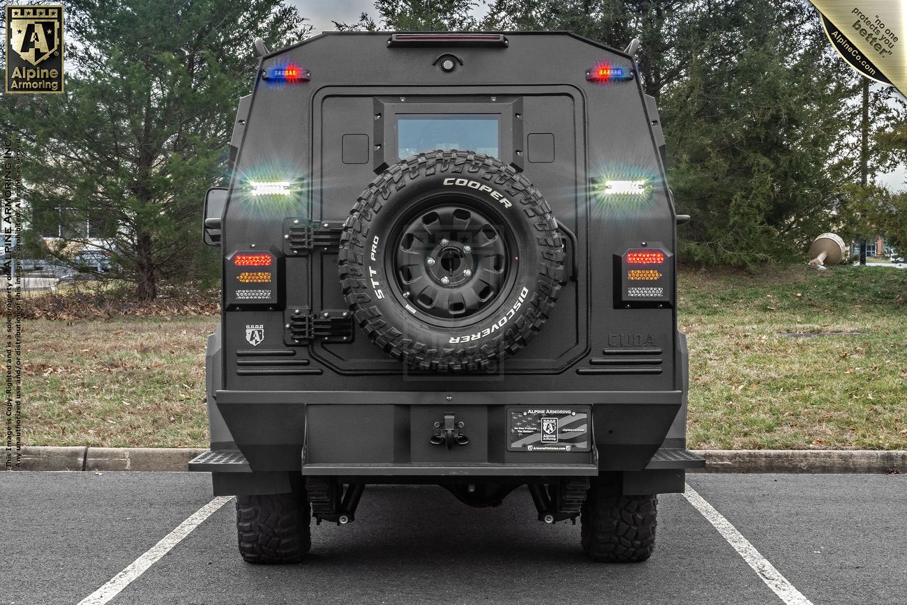 A rear view of a large, armored CUDA SWAT vehicle parked in a lot, featuring off-road tires, emergency lights, and a spare tire mounted on the back door.