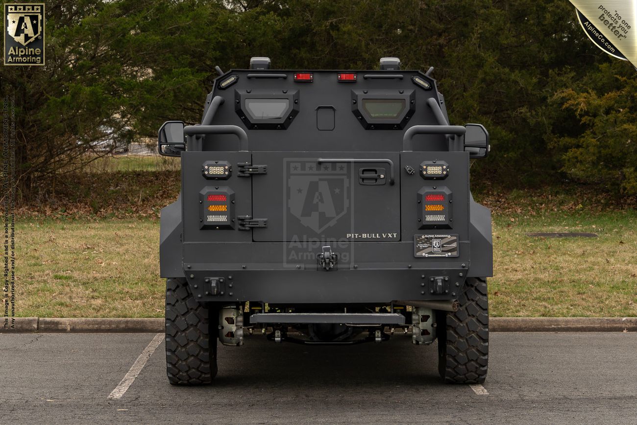 Rear view of a black Pit-Bull VXT SWAT truck parked in an outdoor setting near trees and grass.