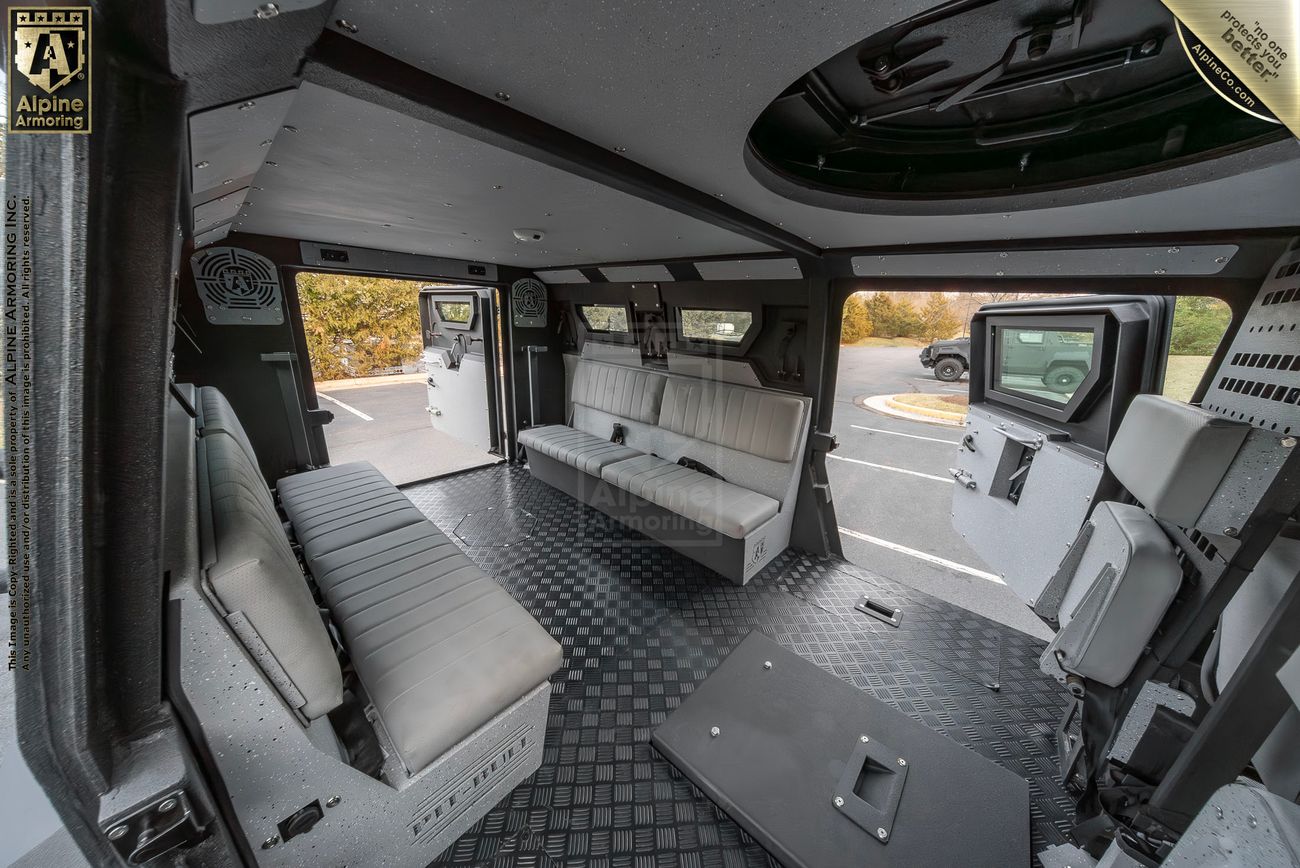 Interior view of aarmored Pit-Bull VX 50 calequipped with bench seating, a monitor, and a mounted weapon hatch, designed for tactical or armored use.