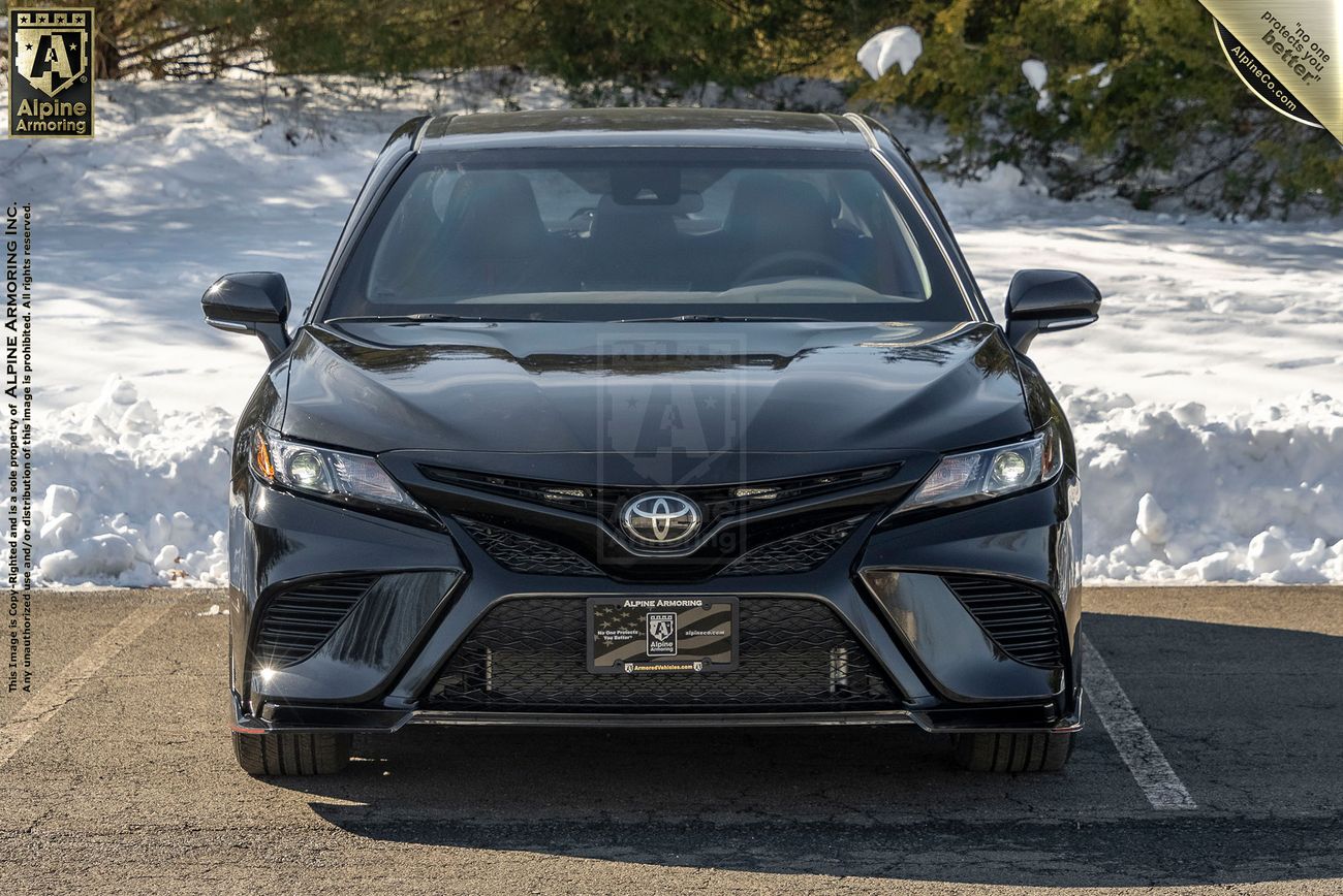 Front view of a parked black armored Toyota Camry TRD sedan in a snowy environment.
