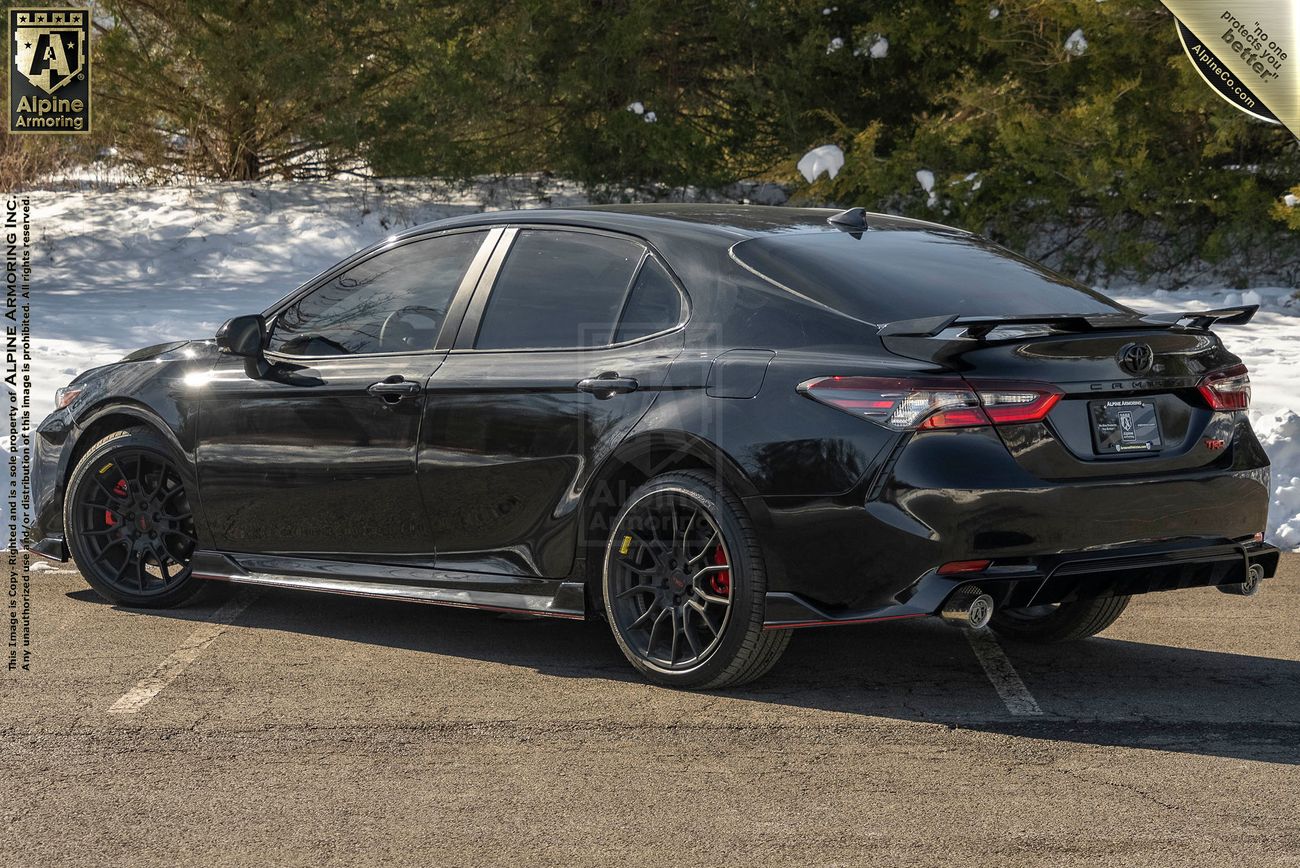 Left side view, from the rear, of an armored Toyota Camry TRD sedan in a snowy environme