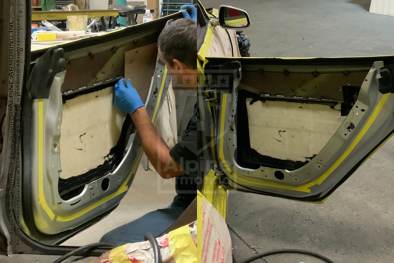 One ndividual works on a car in a workshop. The car is covered in masking tape and paper; one person installing composite kevlar .