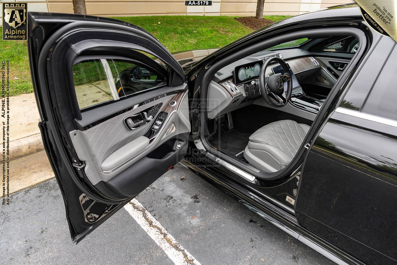 black Mercedes-Benz S580 with its driver door open showing off the grey interior and armored window rolled down partially  