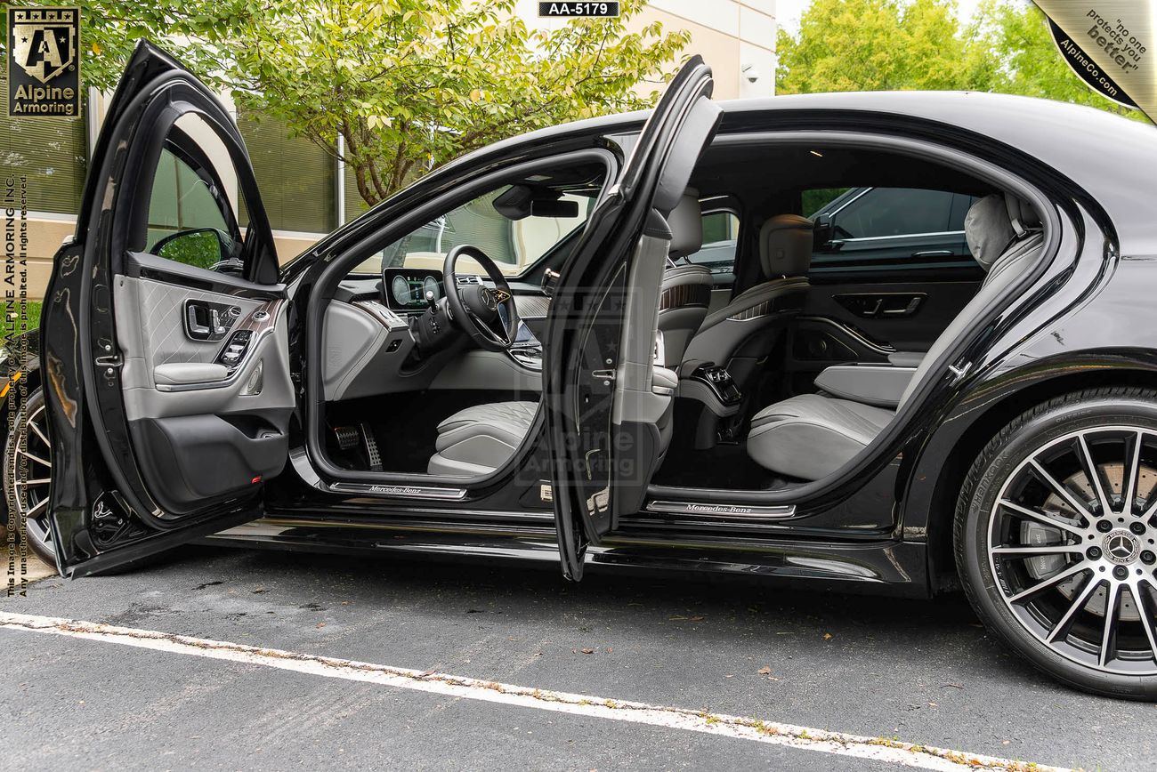 side view of black armored Mercedes-Benz s580 with its driver side doors open displaying its luxurious interior 