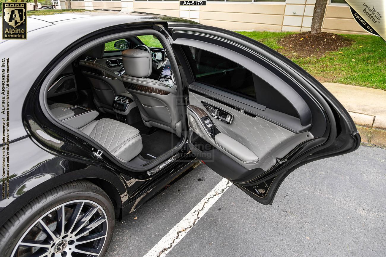 black armored Mercedes-Benz S580 with its rear passenger door open displaying its luxurious interior 
