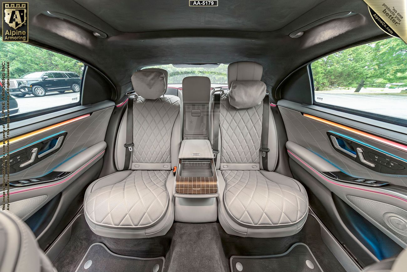 Rear view of the interior of an armored Mercedes-Benz S580 showing its spacious grey and brown interior with attractive lighting 
