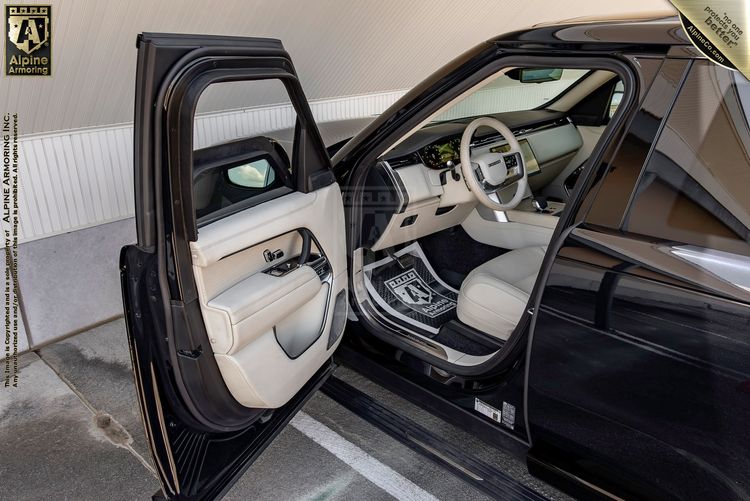 Range Rover Autobiography interior with front doors open, showing cream and navy blue leather seats, wood trim dashboard, and light-colored upholstery.