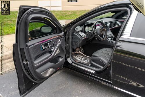 Armored Mercedes-Benz S580 interior with front left door open, showing black leather seats and modern center console.