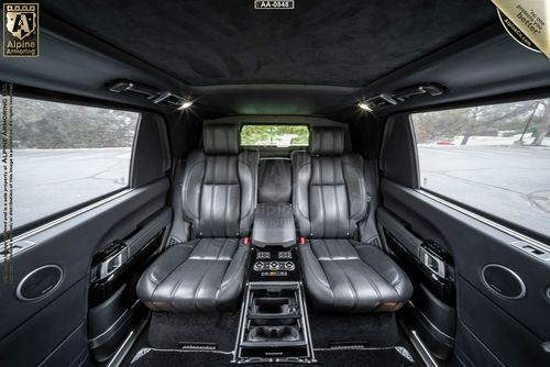 Luxurious car interior featuring black leather seats, a central console with controls, and side windows showcasing an outdoor view.