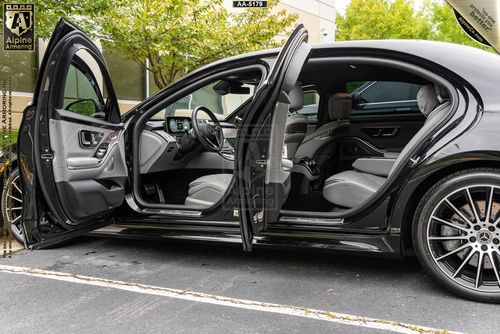 side view of black armored Mercedes-Benz s580 with its driver side doors open displaying its luxurious interior 
